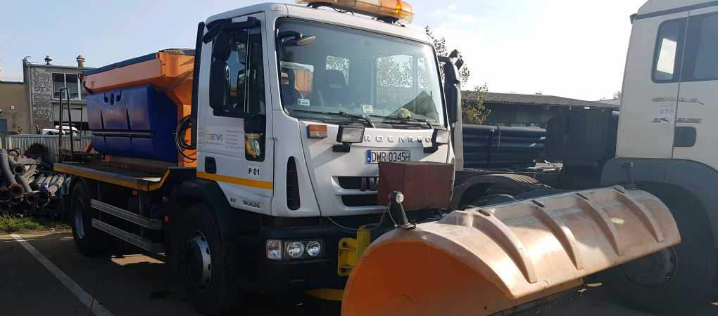 Pługosyparka biało-pomarańczowa na parkingu